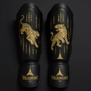 Schwarze Muay Thai Schienbeinschoner mit goldenen Tiger-Motiven, thailändischen Sak-Yant-Symbolen und der Aufschrift 'Vollkontakt' auf schwarzem Hintergrund